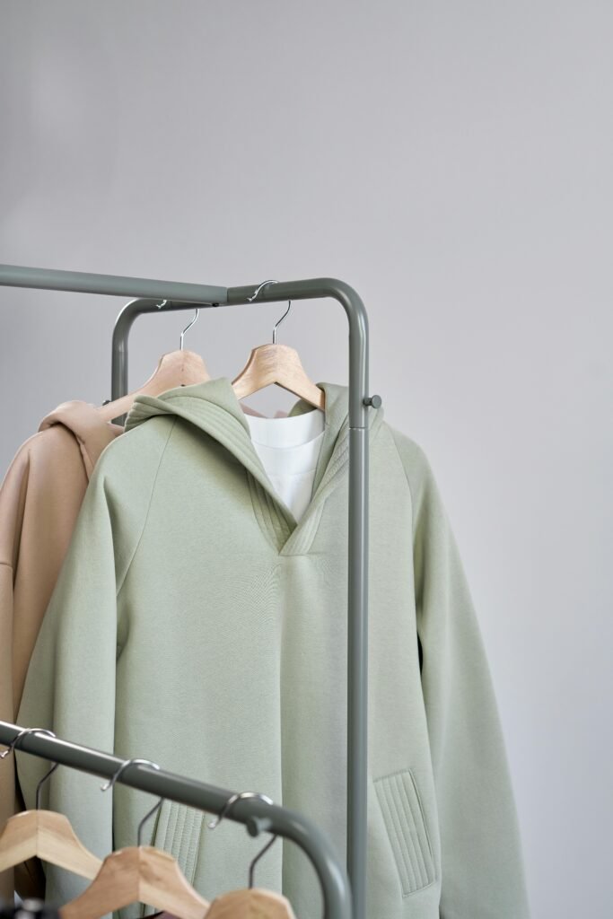 Stylish minimalist sweatshirts displayed on hangers in a studio setting.